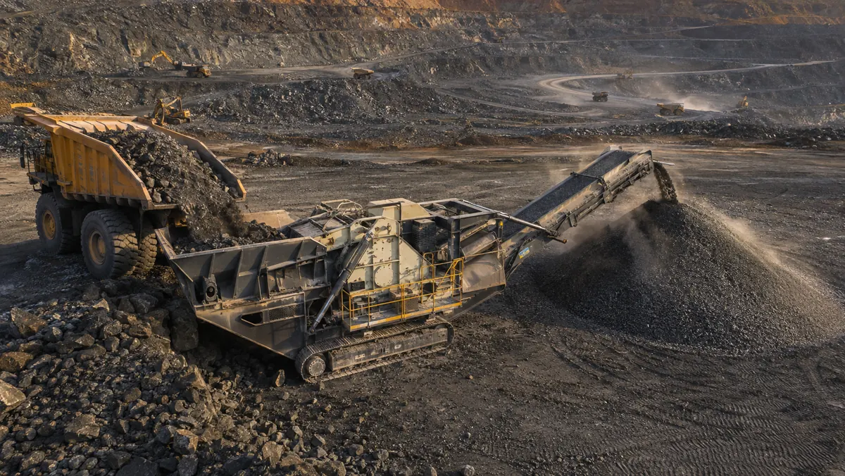 Tracked jaw crusher receiving hard abrasive ore from a haul truck in a stepped open-pit mine